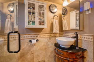 Bathroom featuring tile walls, vanity, and a wainscoted wall