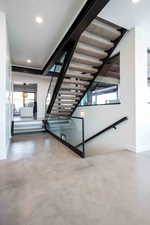 Stairway featuring recessed lighting, healthy amount of natural light, and finished concrete floors