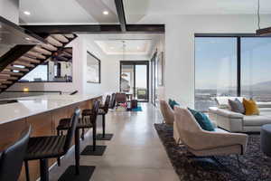 Living room featuring stairs, concrete flooring, a raised ceiling, and recessed lighting