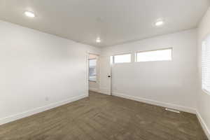 Empty room featuring dark carpet and recessed lighting