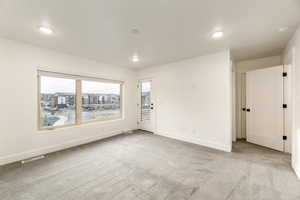 Spare room featuring light colored carpet and recessed lighting