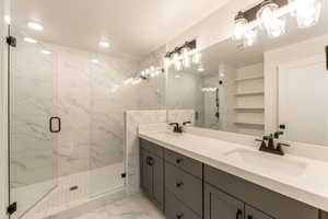 Full bathroom with a marble finish shower, light marble finish floors, and double vanity