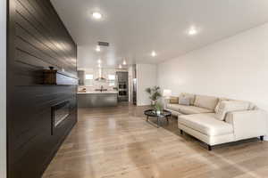 Living area with light wood finished floors and recessed lighting