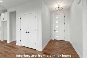 Foyer featuring dark wood-style floors and a chandelier