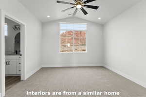 Unfurnished bedroom with light colored carpet, connected bathroom, lofted ceiling, arched walkways, and ceiling fan