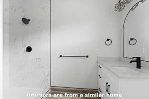 Full bath featuring vanity, a marble finish shower, and wood finished floors