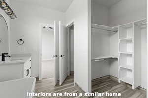 Full bathroom featuring vanity, a soaking tub, light wood finished floors, and a closet