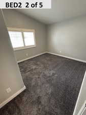 Bedroom 2 with dark colored carpet and vaulted ceiling