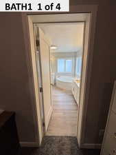 Master Bathroom with a garden tub, vanity, a textured ceiling, and light wood-style floors