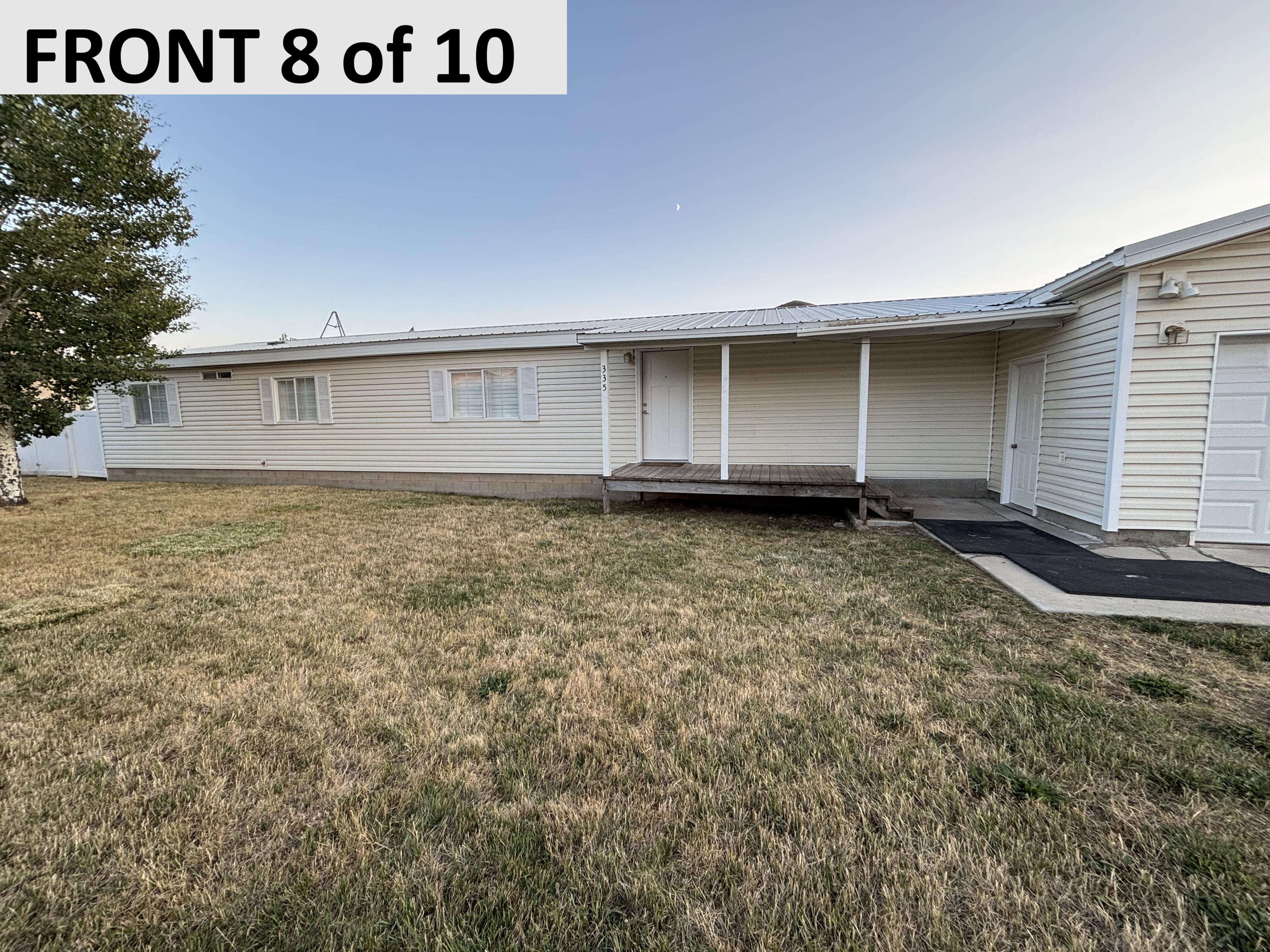 View of front of home with a front lawn, a metal roof, and a deck