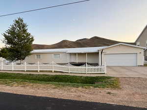 Ranch-style house with a fenced front yard, a garage, concrete driveway, and a mountain view