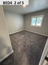 Bedroom 4 featuring dark colored carpet and baseboards