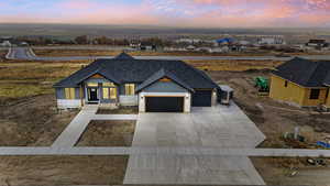 Modern inspired farmhouse featuring an attached garage, driveway, roof with shingles, board and batten siding, and covered porch