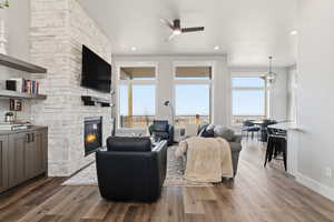 STAGED_Living room featuring dark wood-style floors, ceiling fan, healthy amount of natural light, a fireplace, and recessed lighting