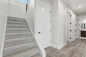 Stairs featuring wood finished floors and recessed lighting
