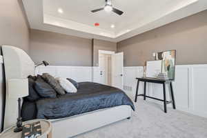 STAGED - Master Bedroom Carpeted bedroom featuring a tray ceiling, a decorative wall, wainscoting, ceiling fan, and recessed lighting