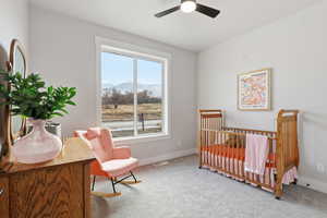 STAGED - Carpeted Bedroom with a mountain view, a nursery area, and ceiling fan