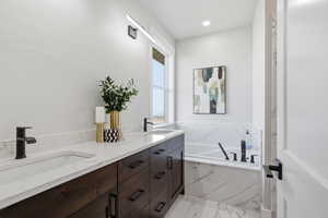 STAGED - Master Bathroom featuring a bath, double vanity, and light marble finish flooring