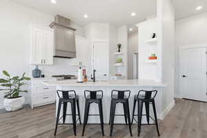 STAGED - Seats 6 total_Kitchen featuring a kitchen bar, a peninsula, tasteful backsplash, open shelves, and light wood-style floors