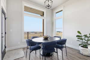 STAGED - Seats 6 Dining area featuring light wood finished floors, view of water and beach, and a chandelier