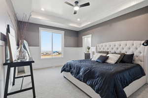 STAGED - Master Bedroom featuring a decorative wall, wainscoting, carpet, a tray ceiling, and a ceiling fan