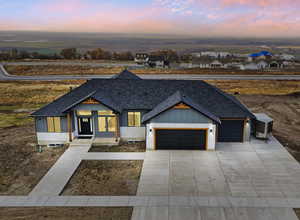 Front of Home_Modern farmhouse featuring a shingled roof, an attached garage, driveway, board and batten siding, and a porch