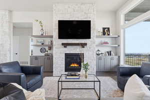 STAGED_Living area featuring a stone fireplace and wood finished floors
