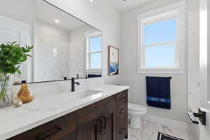 SHARED - Bathroom featuring vanity, light marble finish floors, and a marble finish shower