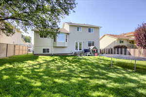 Rear view of house with a fenced backyard, a patio, and a trampoline