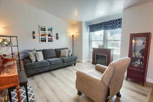 Living area with light wood finished floors, a glass covered fireplace, and a textured ceiling