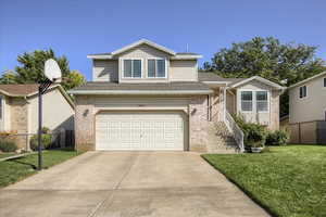 View of front of home with an attached garage, concrete driveway, brick siding, and roof with shingles