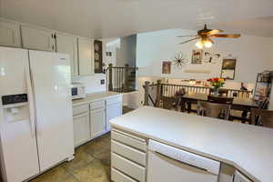 Kitchen featuring white appliances, light countertops, ceiling fan, and white cabinetry