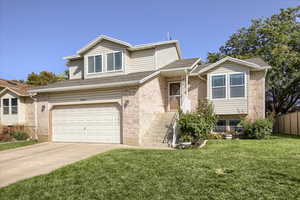View of front facade featuring driveway, a garage, brick siding, and roof with shingles