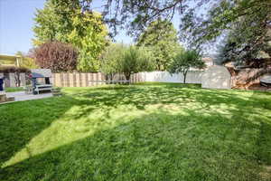 Fenced backyard featuring a storage unit and a trampoline