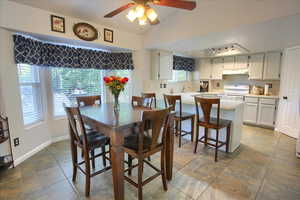 Dining space featuring a ceiling fan, lofted ceiling, and light tile patterned floors