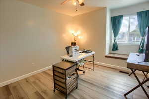 Office with light wood-type flooring and ceiling fan