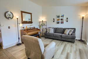 Living room featuring light wood-style flooring and lofted ceiling