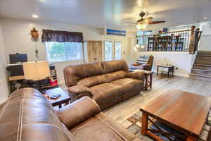Living area featuring wood finished floors, a ceiling fan, stairway, and french doors