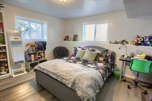 Bedroom with light wood finished floors and a textured ceiling