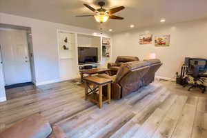 Living room with ceiling fan, light wood finished floors, and recessed lighting