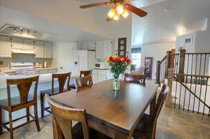 Dining space with a ceiling fan and dark stone finish floors