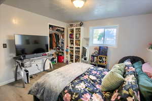Bedroom featuring a textured ceiling, wood finished floors, and a closet