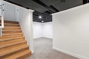 Finished below grade area with light carpet and stairway