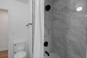 Full bath with shower / bath combination with curtain and toilet
