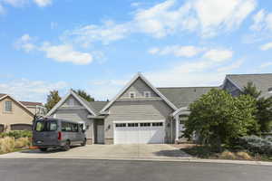 View of front of house with driveway, an attached garage, and stone siding