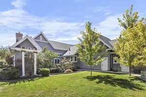 View of front facade featuring a front lawn, a chimney, and roof with shingles