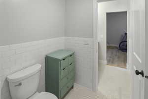 Bathroom with tile walls, wainscoting, and light tile patterned floors