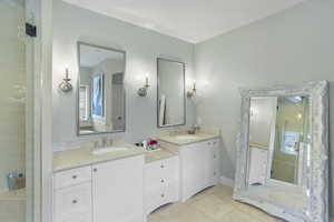 Full bath with light tile patterned flooring, double vanity, and a stall shower