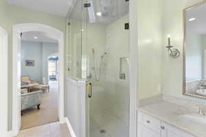 Bathroom featuring a stall shower, vanity, light tile patterned flooring, and recessed lighting
