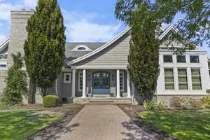 Property entrance with a porch, french doors, a yard, a shingled roof, and brick siding